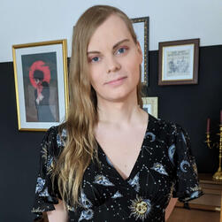 Fiionel mit Blahaj vor einer Progress Pride Flag